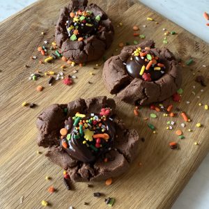 three chocolate cookies on a wooden cutting board