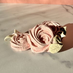 Pink rose piped meringue cookies on a granite countertop